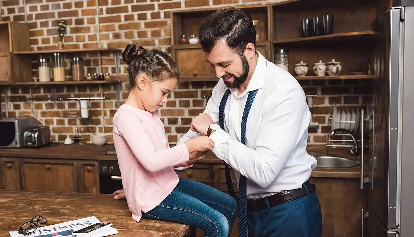 an image of a young girl helping her father fasten his cufflinks